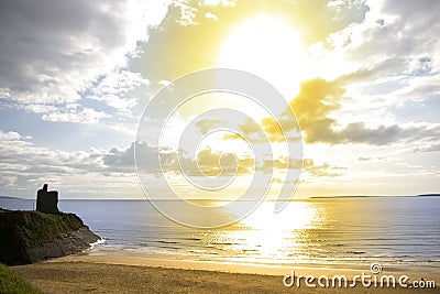 Yellow sun over the Ballybunion beach and castle Stock Photo