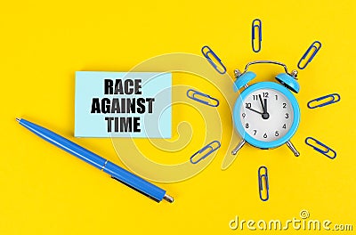 On the yellow surface there is an alarm clock, a pen and stickers with the inscription - Race Against Time Stock Photo