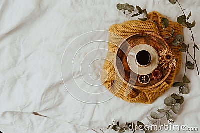 Yellow sweater, wooden tray and coffee cup on bed. Instagram still life trendy photo. Stock Photo