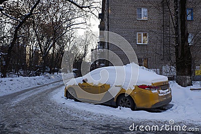 Yellow taxi car of Yandex taxi service covered with snow in a street of Balashikha, Russia. Editorial Stock Photo