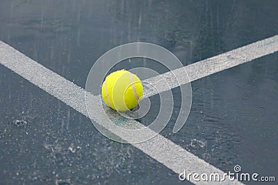 Yellow tennis ball on T line on rainy tennis court Stock Photo