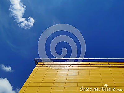 Yellow Tiled Building Exterior Against Blue Cloudy Sky Stock Photo