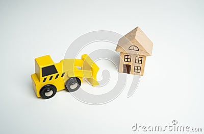 Yellow toy bulldozer and a house. Encroachment on private property. Illegal buildings and construction. Violation of building Stock Photo