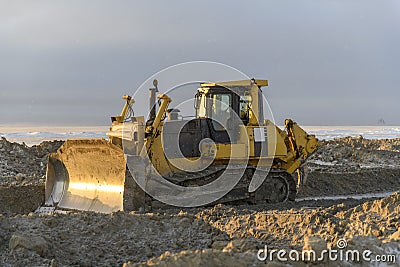 Yellow tractor in winter tundra. The road construction. Bulldozer Stock Photo