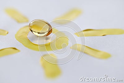 Yellow transparent vitamin D pill lying on drawn sun closeup Stock Photo