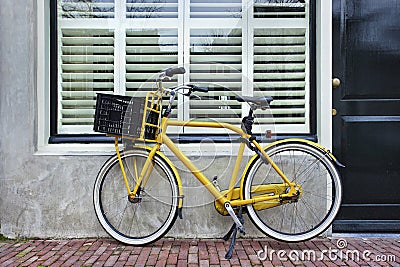 Yellow transport bike parked against renovated house, Amsterdam, Netherlands Stock Photo