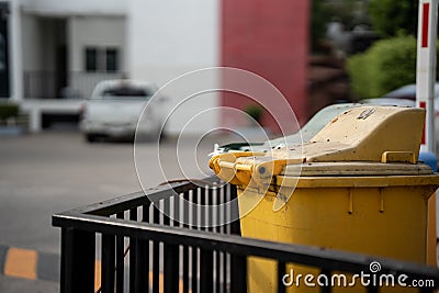 Yellow trash can on a city background Stock Photo