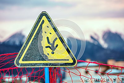 Yellow triangle outdoor warning sign on snowy mountain peaks winter background displaying man falling down a steep as safety peril Stock Photo