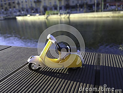 Yellow vespa like model parked in front of the Darsena in Milan Italy Stock Photo