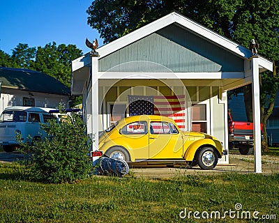 Yellow Volkswagon Bug in front of American Flag Stock Photo