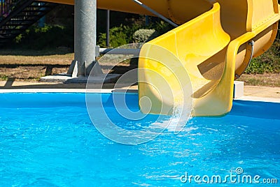 Yellow water slide with blue swimming pool in aqua amusement park during summer warm sunny day Stock Photo