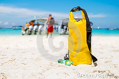 Yellow waterproof shoulder bag with sunglasses on beach sand at Stock Photo