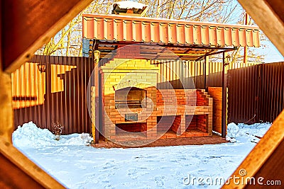 Yellow wooden gazebo with brick grill or barbecue in the yard on a Sunny winter day Stock Photo