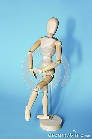 Yellow wooden maniken is dancing and doing poses on blue background Stock Photo