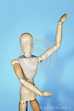 Yellow wooden maniken is dancing and doing poses on blue background Stock Photo