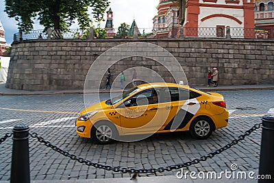 A yellow Yandex-Taxi car rides through the Moscow historic center along a stone-paved street. Antiquity, architecture, vintage Editorial Stock Photo