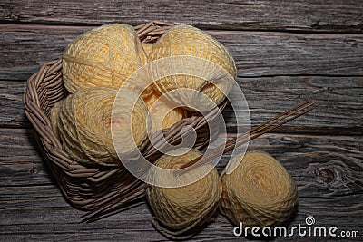 yellow yarns in basket and wooden crochet needle on wooden textured background Stock Photo