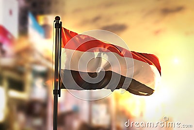 Yemen Flag Against City Blurred Background At Sunrise Backlight Stock Photo