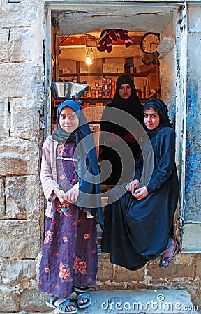 A yemeni woman and two yemeni girls in Thula, village, cistern, wooden door, Yemen Editorial Stock Photo