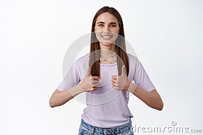 Yes good job. Smiling young woman, client shows thumbs up and nod in approval, agree and like, leave positive good Stock Photo