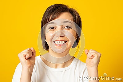 Yes! Happy successful woman winner keeping fists clenched while cheering and feeling lucky, smiling cheerful Stock Photo