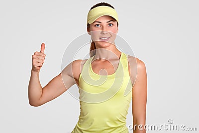 Yes, that was fantastic game! Happy delighted female active player, fond of tennis, makes okay gesture, keeps thumb raised, demons Stock Photo