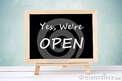 Yes, we& x27; re open on blackboard over green wall background Stock Photo