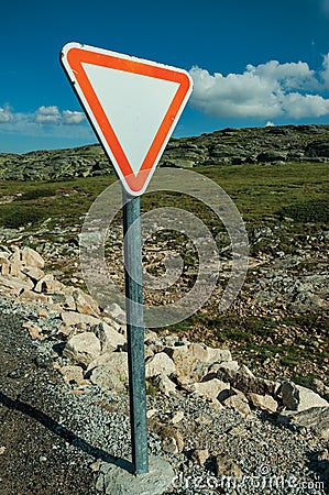 YIELD traffic signpost on roadside and rocky landscape Stock Photo