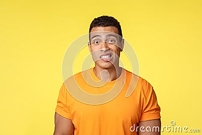 Yikes, awkward. Embarrassed young handsome man caught on lie, feel indesicive and slightly worried, cringe, smiling Stock Photo