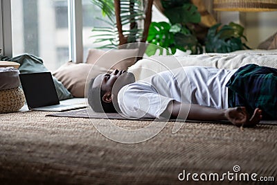 Yoga. African young man meditating on a floor and lying in Shavasana pose. Stock Photo