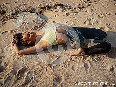 Yoga on the beach. Beautiful woman lying on the sand, practicing Supta Virasana, Reclining Hero Pose. Slim body. Healthy spine. Stock Photo