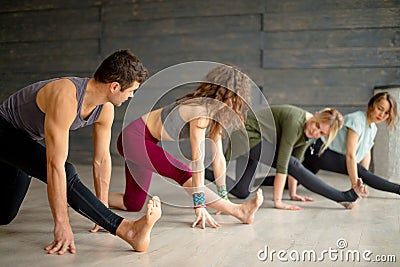 Yoga beginners exercising against grey wall, doing yoga or pilates posture. Stock Photo