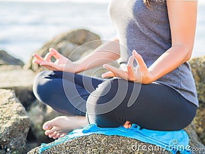 Yoga concept. Closeup woman hand practicing lotus pose on the beach at sunset Stock Photo