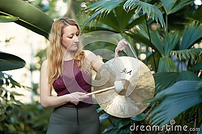 Yoga concept, meditation and sound therapy. Beautiful young caucasian woman performing tibetan gong music therapy. Stock Photo