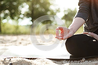 Yoga concept. woman hand practicing lotus pose on the beach at sunset Stock Photo