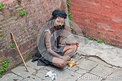 Yoga disciple with dreadlocks having breakfast on the ground Editorial Stock Photo