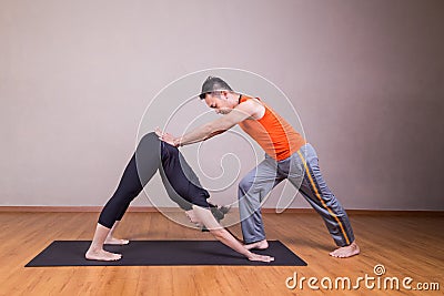 Yoga instructor guiding student perform downward facing dog pose Stock Photo