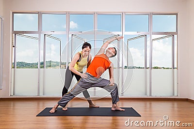 Yoga instructor guiding student perform extended side angle pose Stock Photo