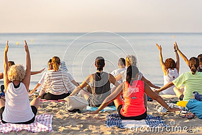 Yoga instructor leading a group session at sunset on the beach in Altafulla, Tarragona, Spain Editorial Stock Photo