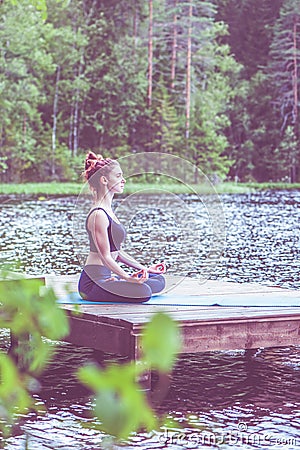 Yoga meditation by yogi girl on the pier of a beautiful lake. The concept of appeasement, healthy lifestyle Stock Photo