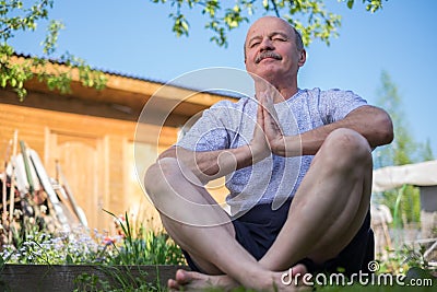 Yoga at park. Senior man with mustache with namaste sitting.Concept of calm and meditation. Stock Photo