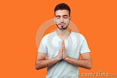 Yoga practice for mind balance. Portrait of peaceful handsome brunette man meditating. indoor studio shot isolated on orange Stock Photo