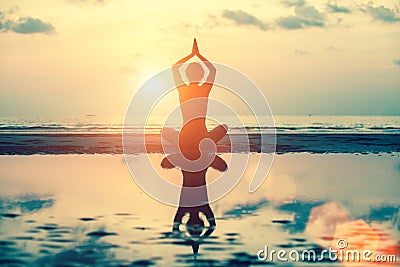 Yoga silhouette. Meditation girl on the background of sea during sunset. Stock Photo