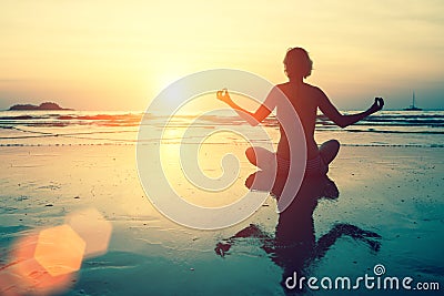 Yoga silhouette. Meditation girl on the sea during sunset. Stock Photo