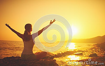 Yoga at sunset on beach. woman doing yoga Stock Photo