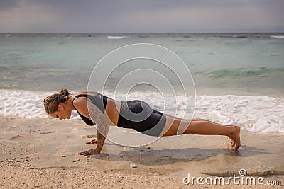 Yoga woman on the beach. Caucasian woman practicing Phalakasana, Plank Pose. Strong body. Healthy lifestyle. Self-care concept. Stock Photo
