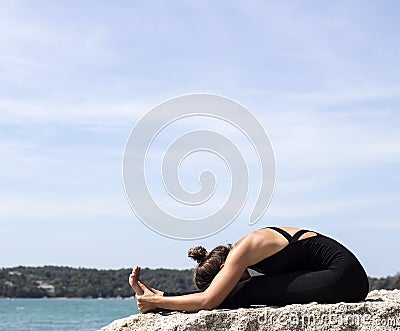 Yoga woman poses on beach near sea and rocks Stock Photo