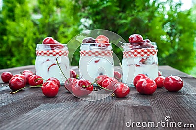 Yogurt with Cherry and strawberries, square. Berries of blueberries and strawberries are scattered on the table. Stock Photo