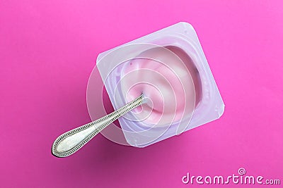 Yogurt cup with pink yoghurt and spoon on bright pink background Stock Photo