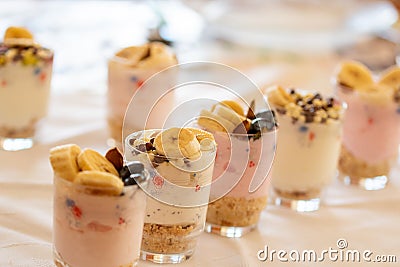 Yogurt dessert with different fruits, crushed cookie and chocolate, presented in crystal glasses decorated with floral elements Stock Photo